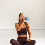 Sitter på Radiant Health infrarød matte og drikker vann etter behandling.