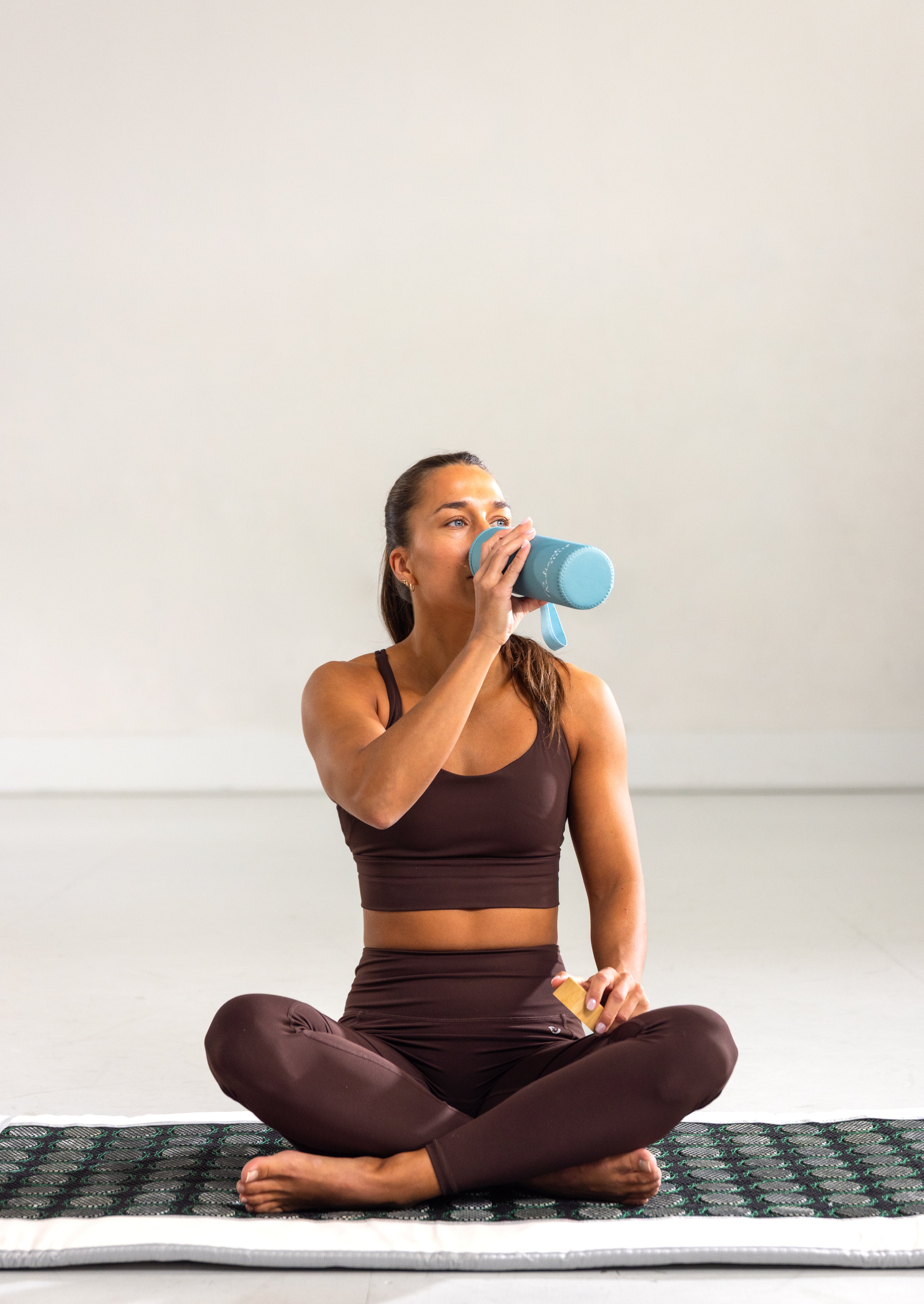 Sitter på Radiant Health infrarød matte og drikker vann etter behandling.