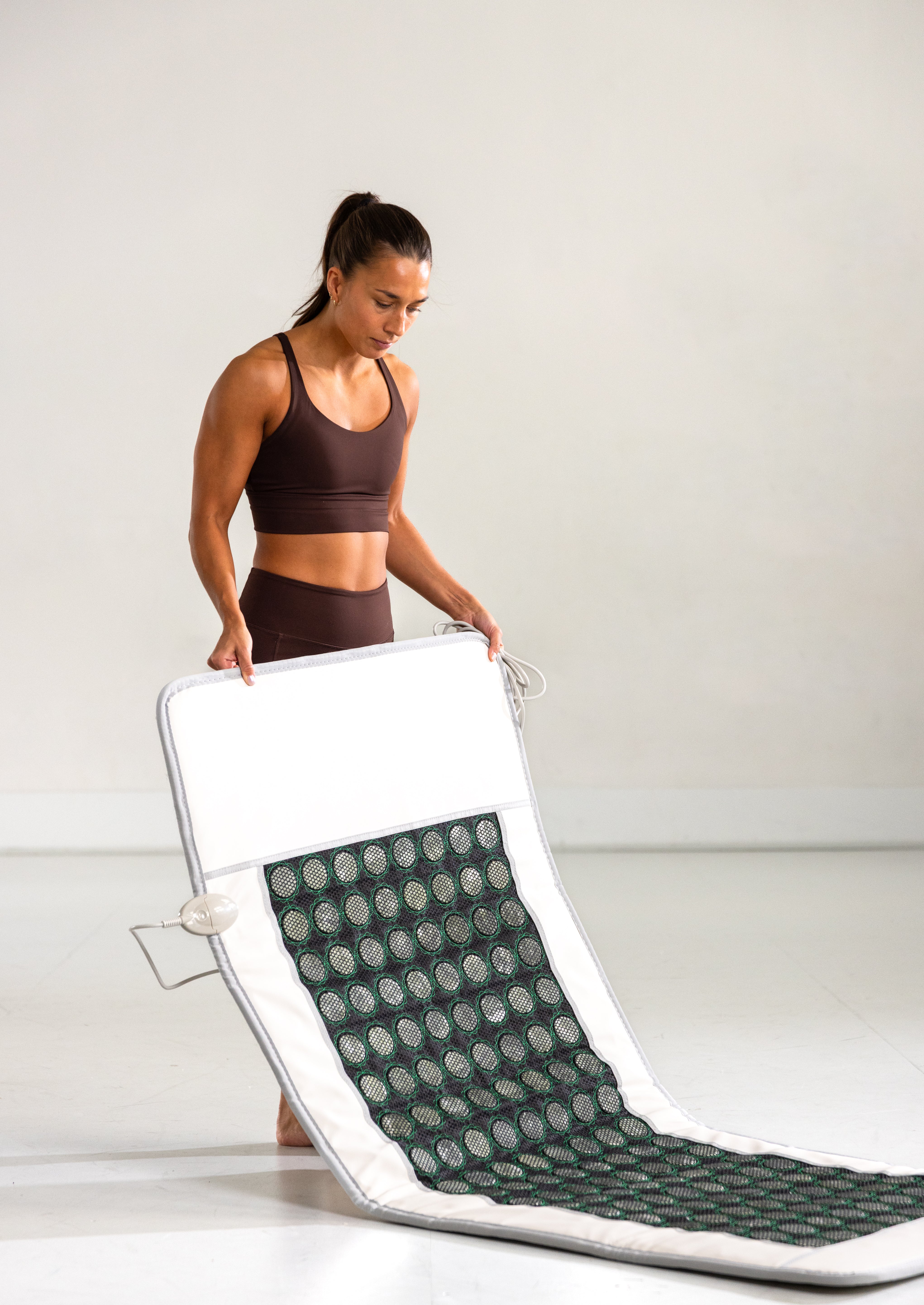 Kvinne viser hvor enkelt det er å brette sammen Radiant Health infrarød matte.