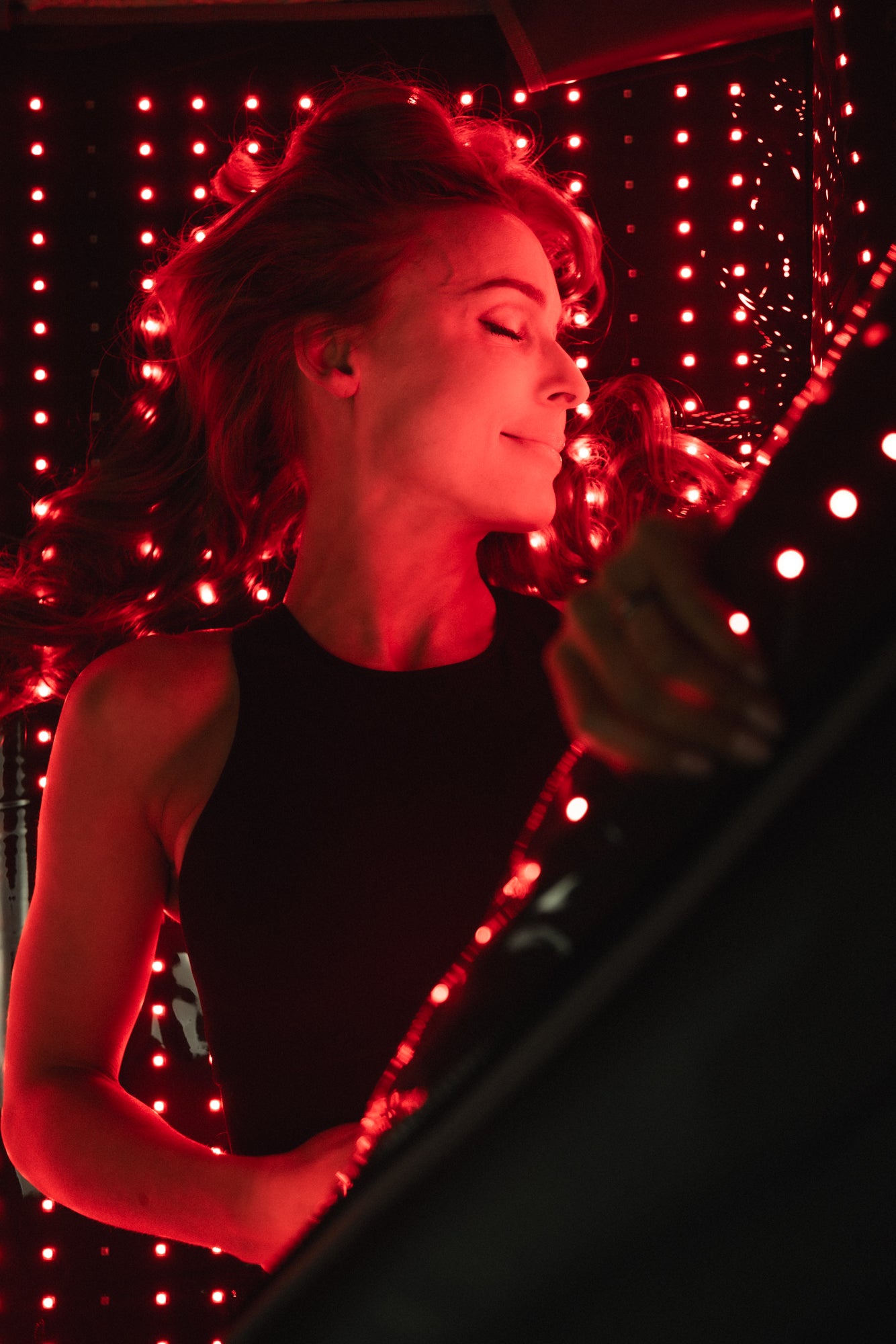 Kvinne nyter LumaRed Mat med intense røde LED-lys. Behandlingen kan stimulere musklene, øke sirkulasjonen og gi en følelse av ro og energi.