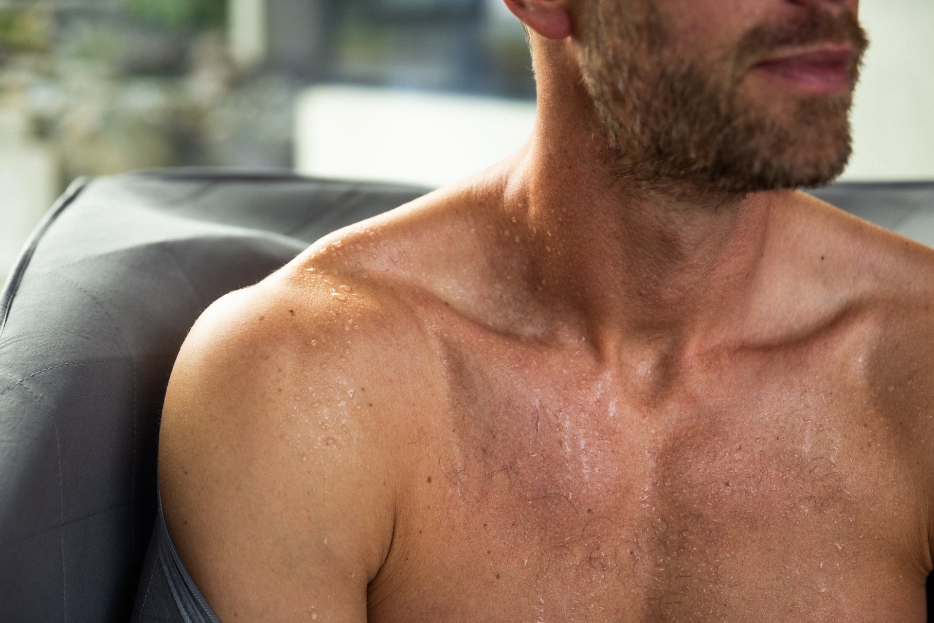 Mann med svetteperler på bryst og skuldre etter sauna. Viser kroppens naturlige respons på varmebehandling med økt sirkulasjon og avgiftning.