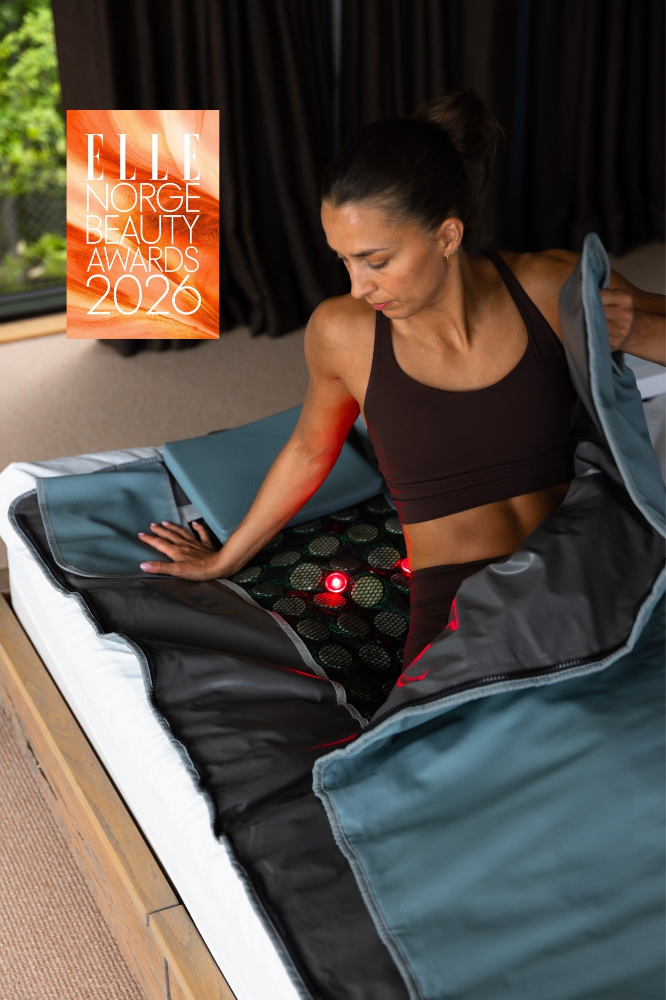 Kvinne som bruker LumaRed infrarødt saunateppe fra Radiant Health med rødlysterapi hjemme – vinner av ELLE Norge Beauty Awards 2026