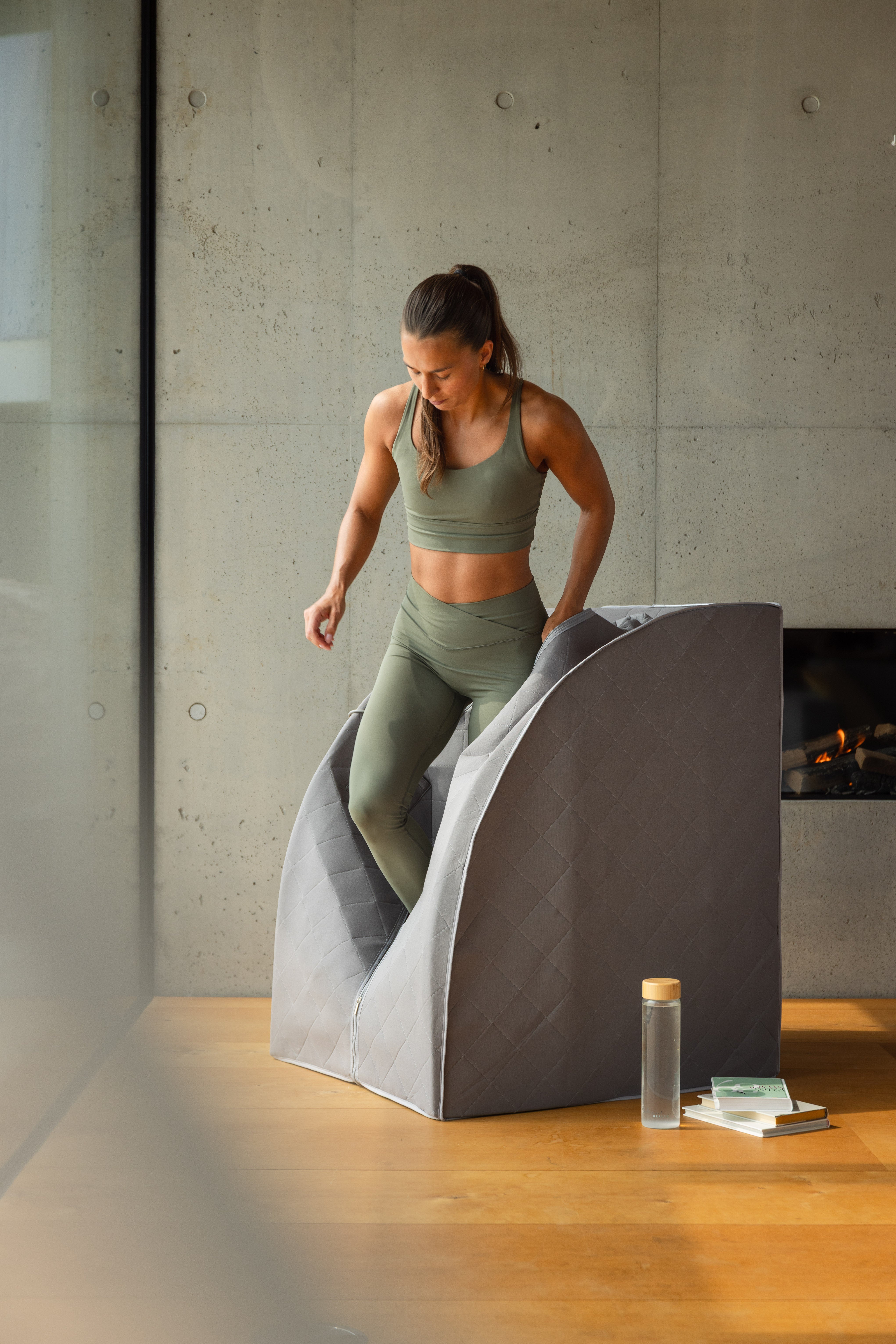 Kvinne i treningsklær bruker grå Radiant Health infrarød sauna hjemme.