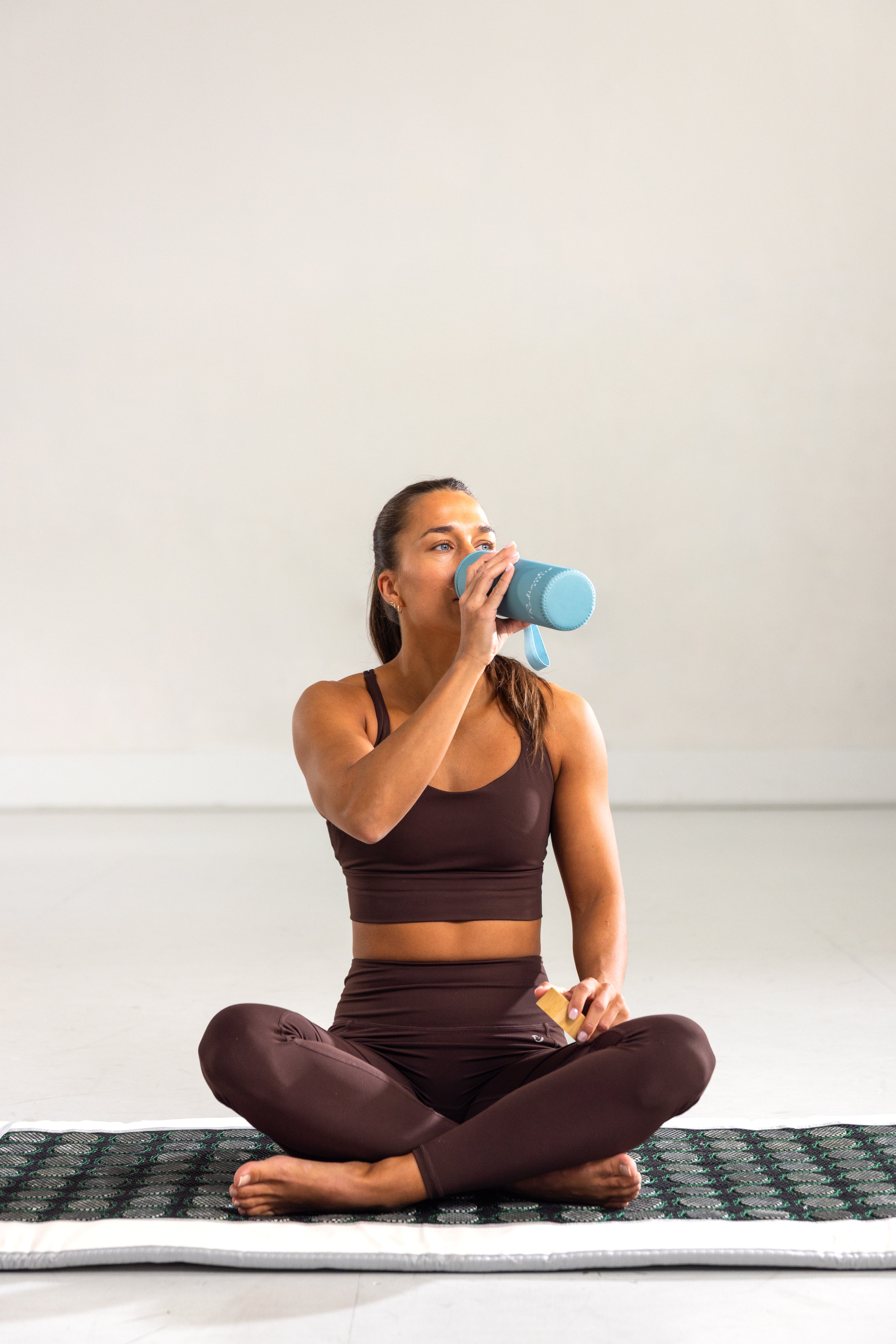 Sitter på Radiant Health infrarød matte og drikker vann etter behandling.