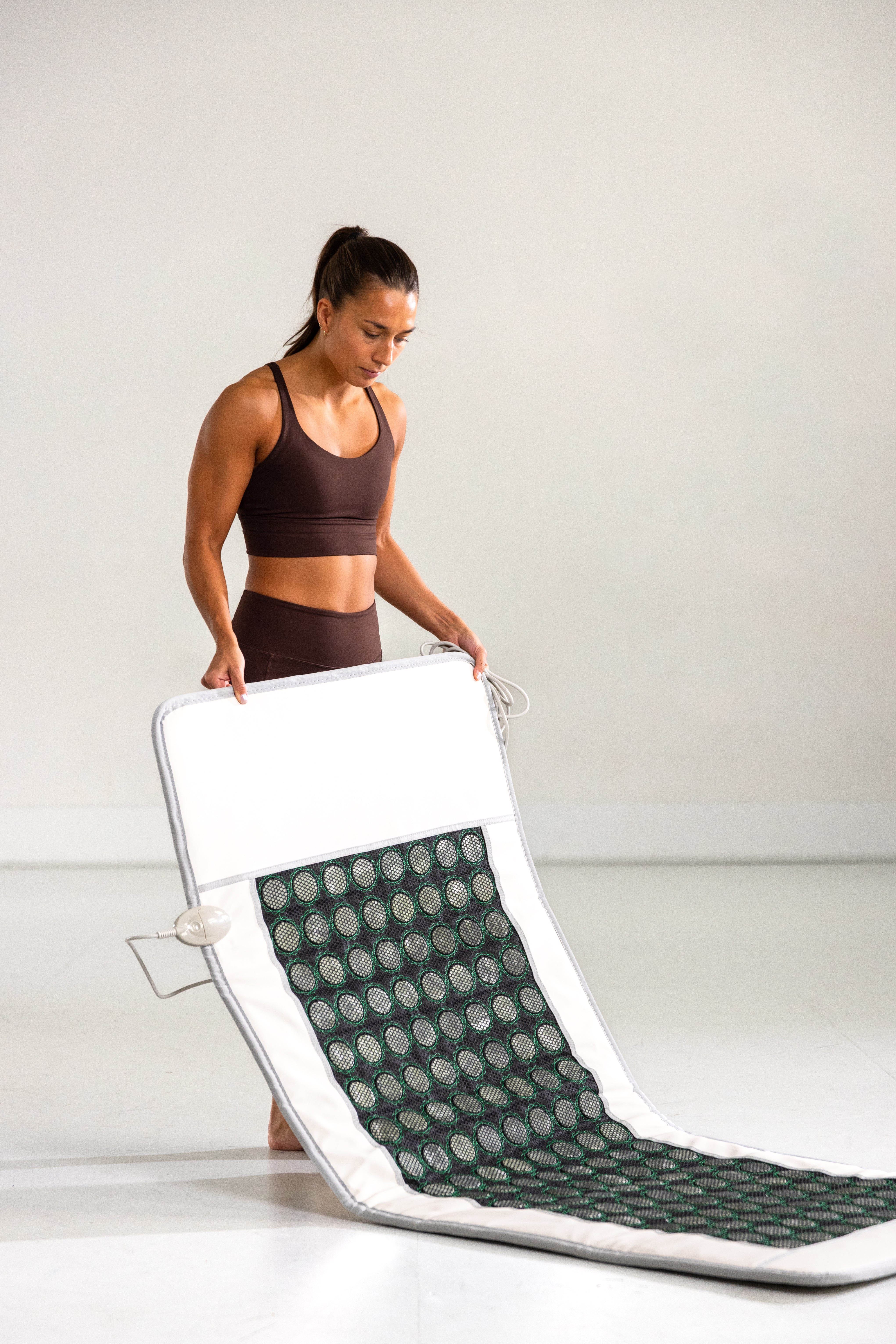 Kvinne viser hvor enkelt det er å brette sammen Radiant Health infrarød matte.