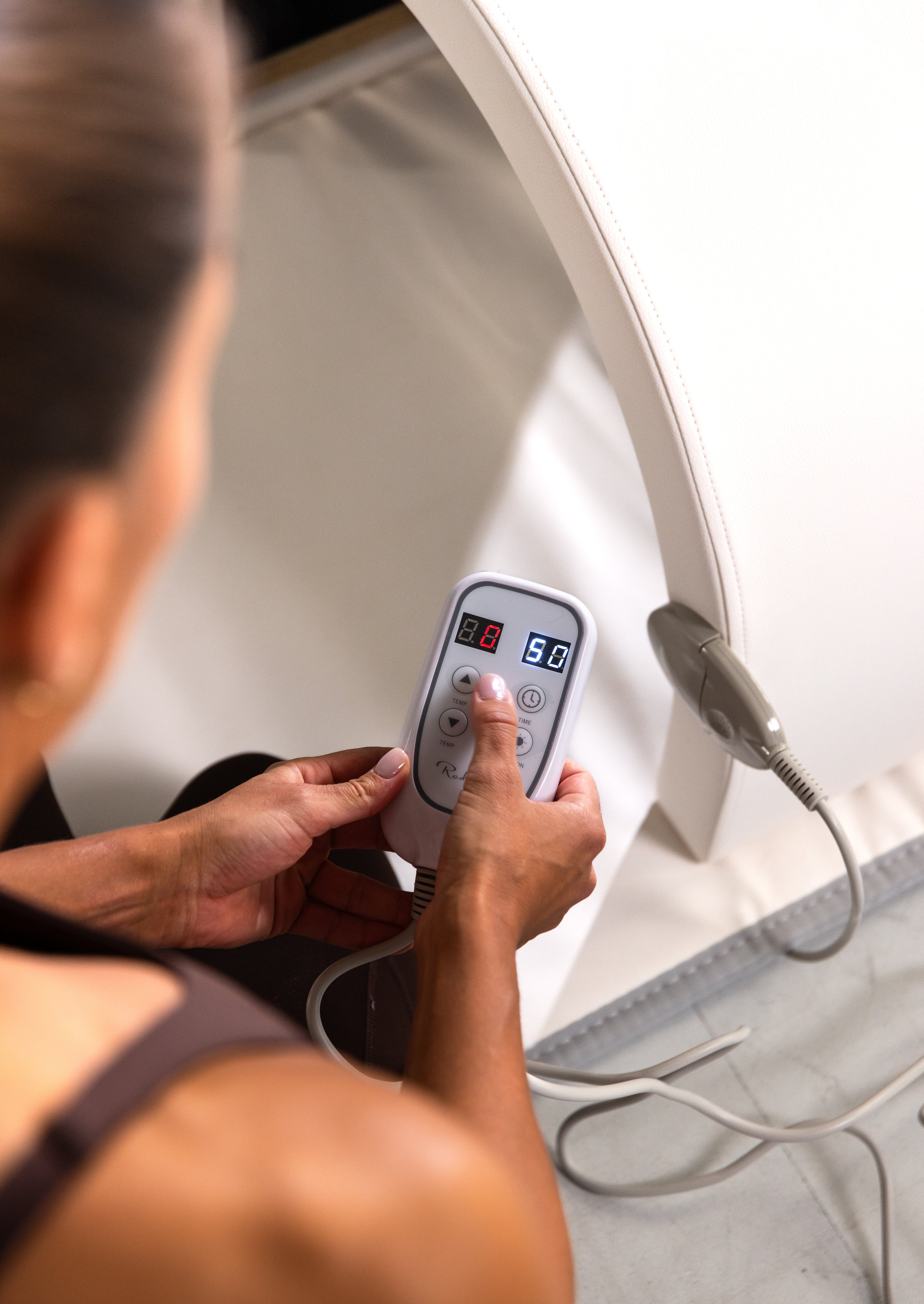 Justerer temperatur på Radiant Health infrarød terapi-enhet med håndkontroll.