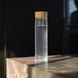 Minimalistisk glassflaske med naturinspirert lokk. Miljøvennlig og funksjonell design.