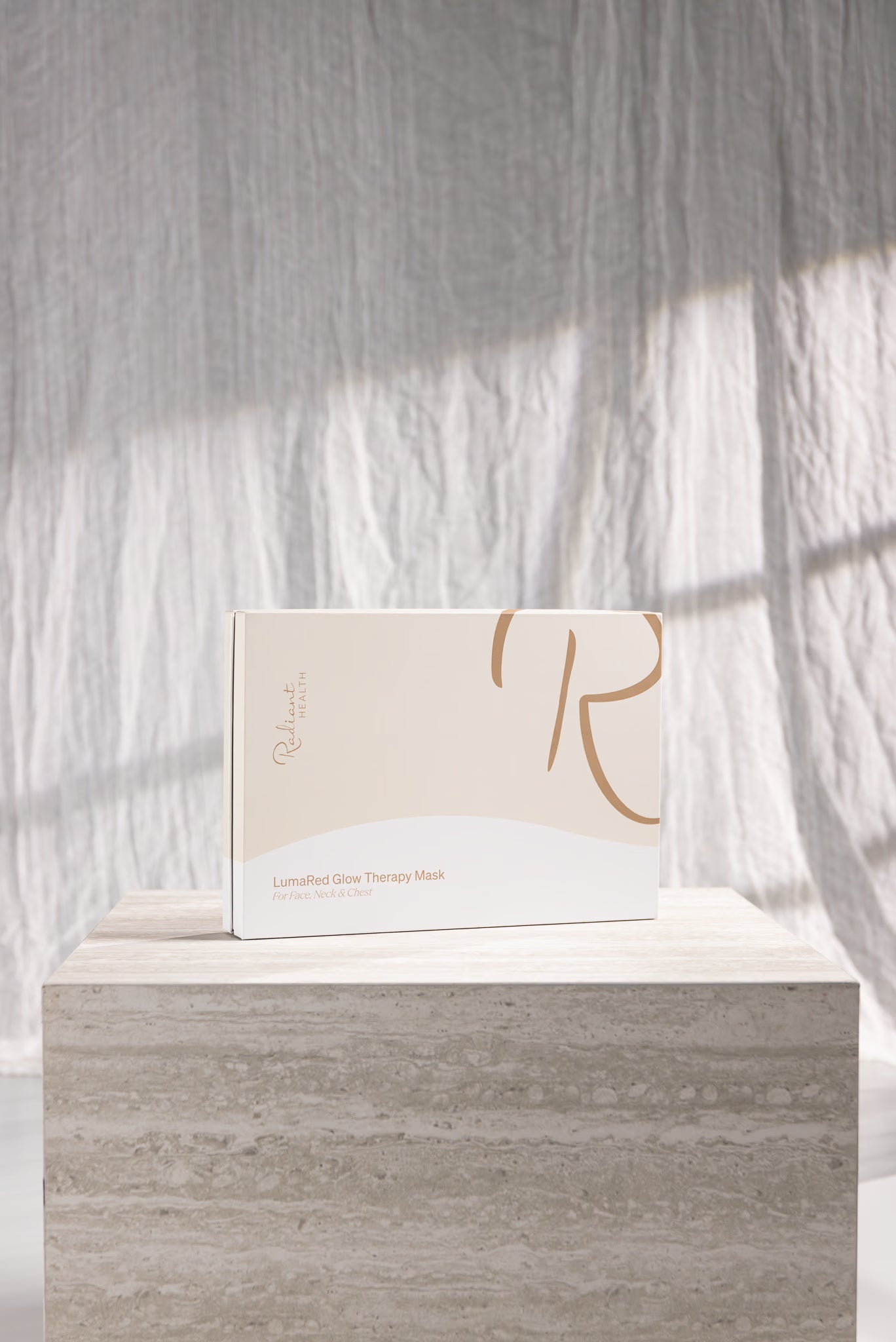 Emballasje til LED-lysterapimaske fra Radiant Health (LumaRed Glow Therapy Mask) på marmorblokk i lyst