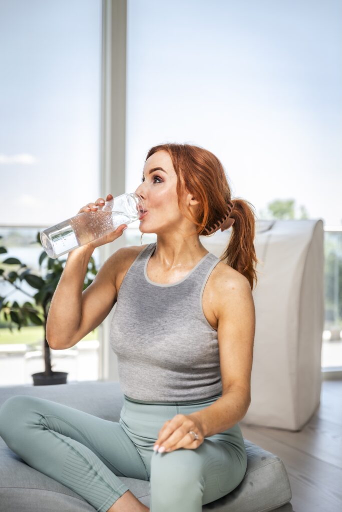 Kvinne drikker vann fra Radiant Health-flaske etter trening